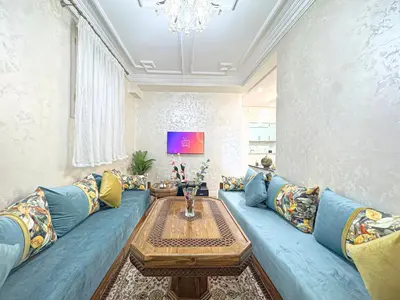 a living room with a blue couch and a table at Havre de calme - Cour & 2 chambres in Marrakech