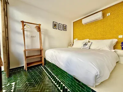 a bedroom with a white bed and a yellow wall at Riad des bibouches pool breakfast private in Marrakech