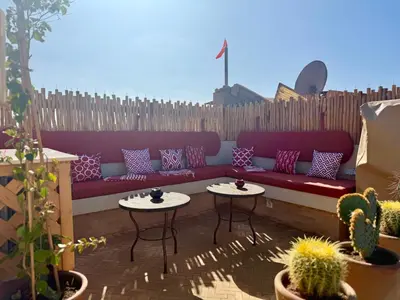 a patio with a couch and two tables and cactus at Riad des bibouches pool breakfast private in Marrakech