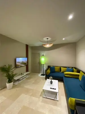 a living room with a blue couch and a tv at Red city charm - city center apartment in Marrakech