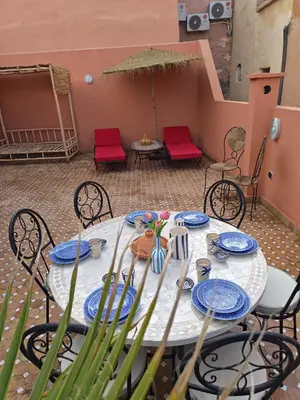 a white table with blue plates and red chairs at Riad Dar Barka Privatisé 3 chambres in Marrakech
