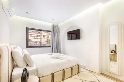 a white bedroom with a bed and a window at Sweet Clarity Swimming pool and Parking in Marrakech