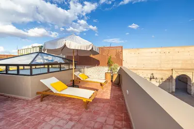 a patio with two chairs and an umbrella on a roof at Riad Mimouna - Rooftop view & Breakfast included - 4 Rooms - Fully private in Marrakech