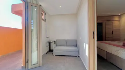a bedroom with a chair and a bed and a mirror at Lovely studio 4th floor No Elevator in El Gouassem