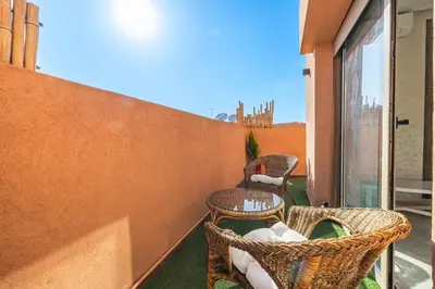 a balcony with wicker chairs and tables on a building at Charming 1-BR with Terrace, AC, Parking-City Center in Marrakech