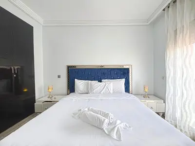 a bedroom with a large white bed with two night stands at Le Cosy Urbain - Proche centre, Parking & Balcon in Marrakech