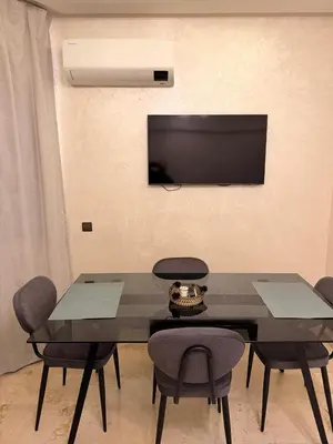 a dining room with a table and chairs and a television at Appart Cosy et confort en plein centre Marrakech in Marrakech