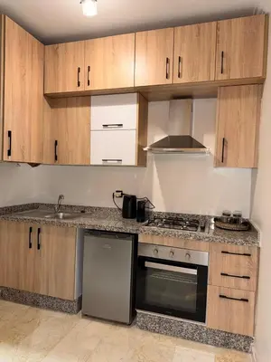 a kitchen with wooden cabinets and a stove top oven at Appart Cosy et confort en plein centre Marrakech in Marrakech