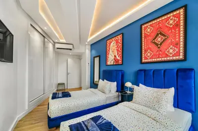two beds in a room with a blue wall at Downtown Cozy Apartment with Panoramic View in Marrakech