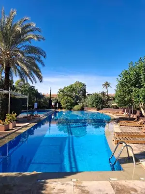 a large swimming pool with blue water and palm trees at Palmeraie Garden Luxury Appartement Family Only in Marrakech