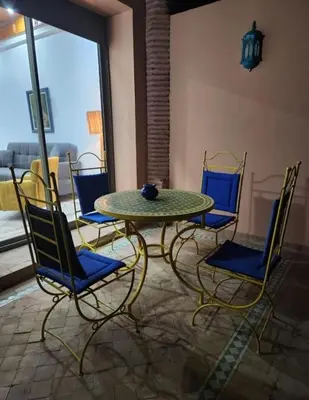 a table and chairs in a room with a window at Palmeraie Garden Luxury Appartement Family Only in Marrakech