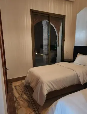 a bedroom with two beds and an arched doorway at Palmeraie Garden Luxury Appartement Family Only in Marrakech