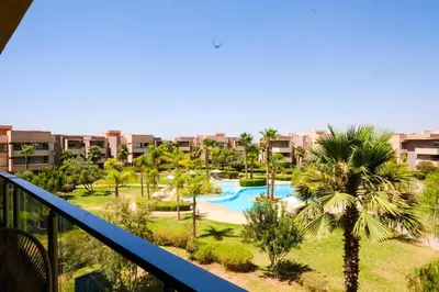 a view of a resort with a swimming pool and palm trees at Prestigia Appartment Golf & 3 Pools in Marrakech