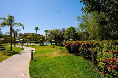 a path through a park with flowers and palm trees at Prestigia Appartment Golf & 3 Pools in Marrakech