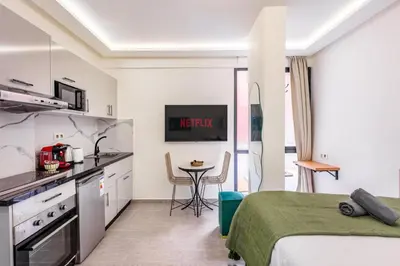 a bedroom with a bed and a kitchen with a table at Studio chic et cosy au cœur de Guéliz in Marrakech