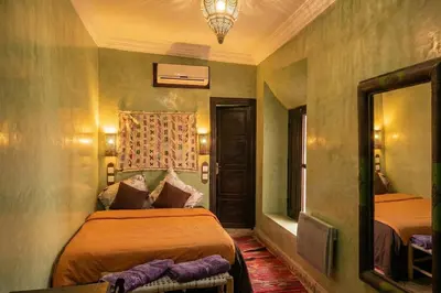 a bedroom with two beds and a mirror at Riad Lana Marrakech - Dar el Bacha Luxury Suites in Marrakech