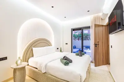 a white bedroom with a large bed and a tv at Le Nid de Guéliz Private terrace and silence in Marrakech