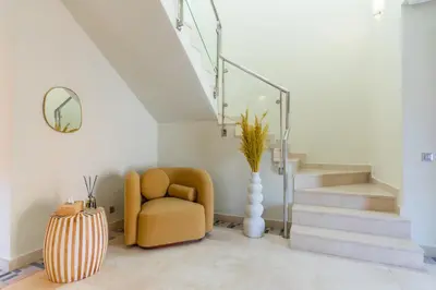a living room with a chair and a staircase at Private Pool Villa Facing Golf Luxury inMarrakech in Marrakech