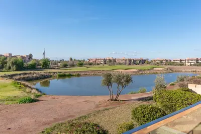 a pond with a tree in the middle of a field at Private Pool Villa Facing Golf Luxury inMarrakech in Marrakech