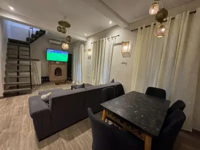 a living room with a couch and a table and a tv at Duplex Bahia Palace in Marrakech