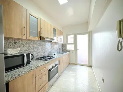 a kitchen with wooden cabinets and a microwave at Confort Signature - Piscine, balcon & parking in Marrakech