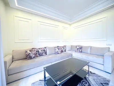a living room with a couch and a table at Confort Signature - Piscine, balcon & parking in Marrakech