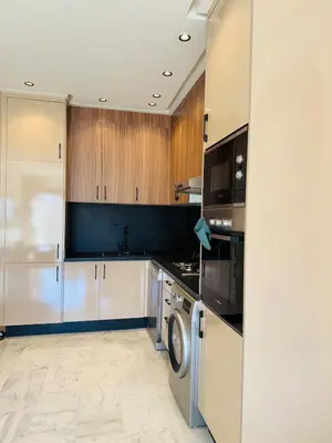 a kitchen with wooden cabinets and a washer and dryer at Refined apartment with rooftop pool in Marrakech