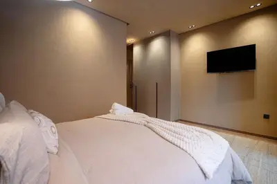a bedroom with a white bed and a flat screen tv at Spacious duplex Private HEATED pool Jacuzzi in Marrakech