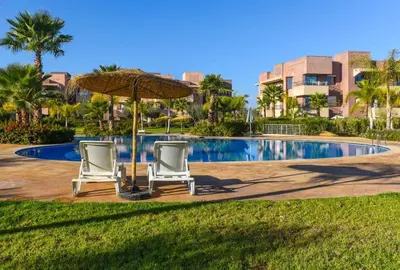 two chairs and an umbrella next to a swimming pool at Prestigia Jade in Marrakech