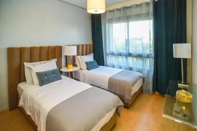 two beds in a hotel room with a window at Prestigia Jade in Marrakech