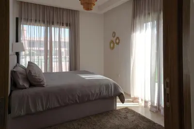 a bedroom with a bed and a large window at Appartement 2 chambres avec grand jardin Noria Golf in Marrakech