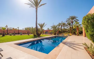 a swimming pool in a yard with palm trees at Rixos Palm villas with a heated private pool & garden in Marrakech