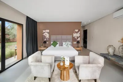 a bedroom with a bed and two chairs at Rixos Palm villas with a heated private pool & garden in Marrakech
