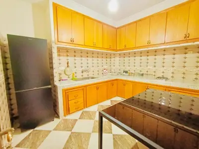 a kitchen with wooden cabinets and a black refrigerator at Nice apart wi-fi 3rd floor in El Gouassem