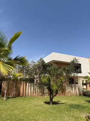 a house with a tree in front of a fence at Exceptional Villa Noria Golf in Marrakech