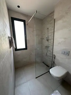 a bathroom with a shower and a toilet and a window at Luxury villa Noria golf club in Marrakech