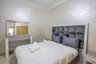a bedroom with a large white bed and a mirror at Family apartment Jardins Chrifia in Marrakech