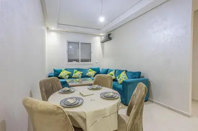 a dining room with a table and a blue couch at Family apartment Jardins Chrifia in Marrakech