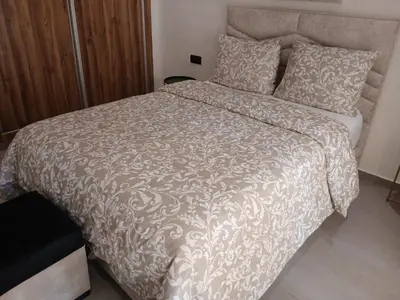 a bedroom with a bed with a brown and white comforter at Appartement Cozy Hivernage in Marrakech