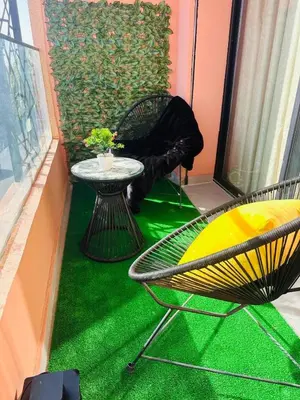 a balcony with a table and chairs on a green floor at Appartement Cozy Hivernage in Marrakech