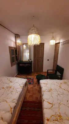 a bedroom with two beds and a chandelier at Hotel & Riad Celia in Marrakech