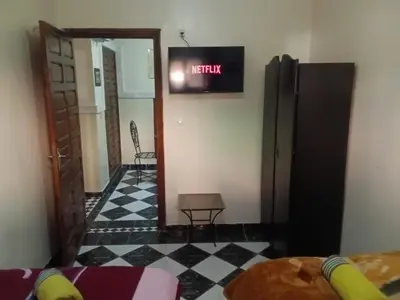 a room with a tv on the wall and a table at Appartement Chez Anita in Marrakech