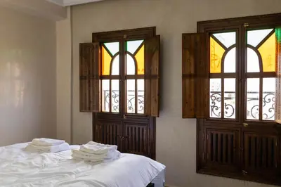 a bedroom with two windows and a bed with white sheets at la roseraie Marrakech in Marrakech