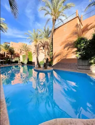 a swimming pool with blue water and palm trees at Riad Authentique à quelques pas de Jamaa El-Fna in Marrakech