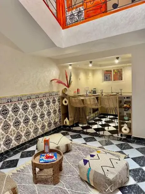 a living room with a table and a kitchen at Riad Authentique à quelques pas de Jamaa El-Fna in Marrakech