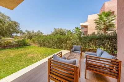 two wooden benches sitting on a deck with a yard at Magnifique appartement rez-de-jardin face piscine in Marrakech