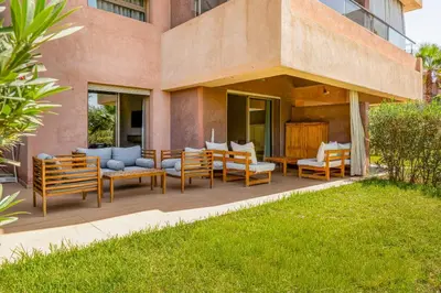 a patio with chairs and tables in front of a building at Magnifique appartement rez-de-jardin face piscine in Marrakech