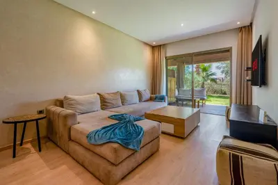 a living room with a couch and a table at Magnifique appartement rez-de-jardin face piscine in Marrakech