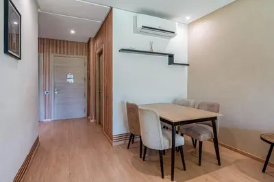 a dining room with a wooden table and chairs at Magnifique appartement rez-de-jardin face piscine in Marrakech