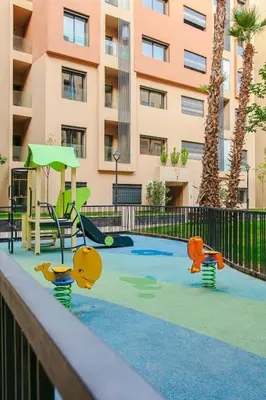 a playground in front of a building with palm trees at Inside A Mood - Marrakech in Marrakech